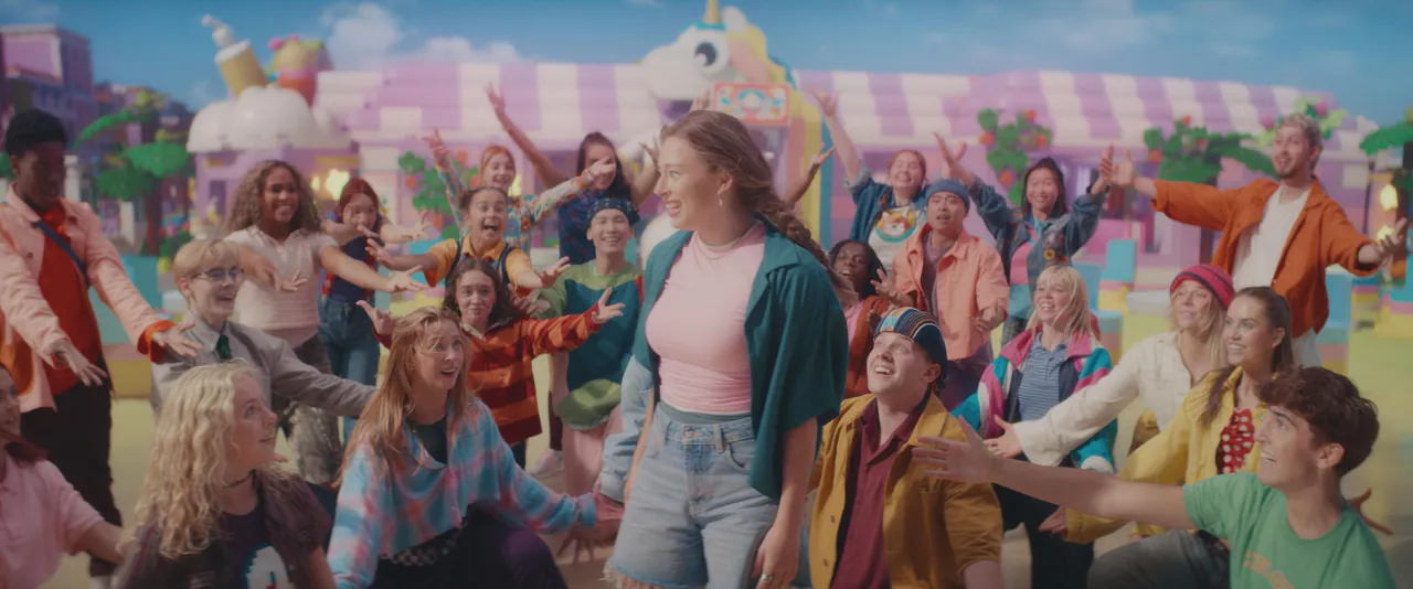 Junges Ensemble des LEGO Friends Musicals tanzt in einer bunten Straße von Heartlake City