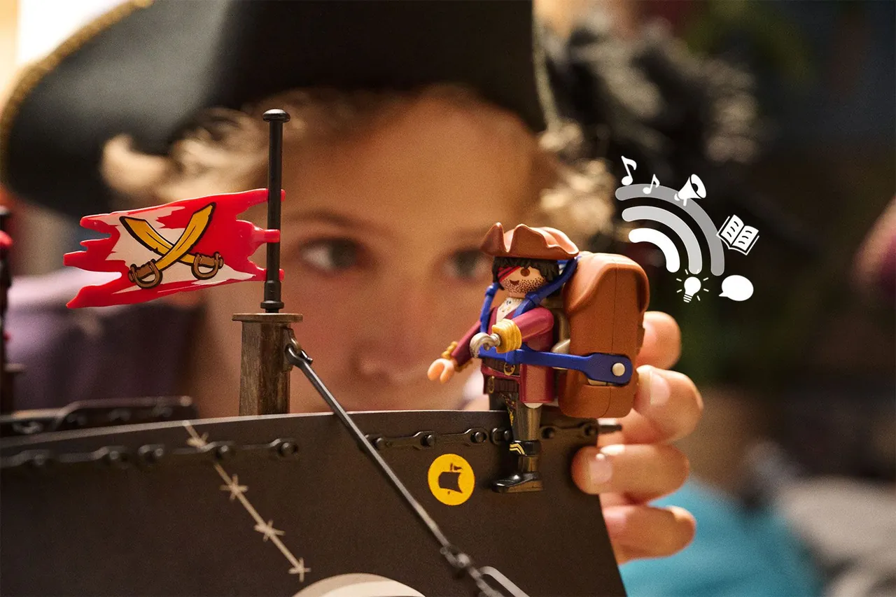 Kind hält eine Playmobil-Piratenfigur mit dem Audio-Rucksack von Playmobil hi!