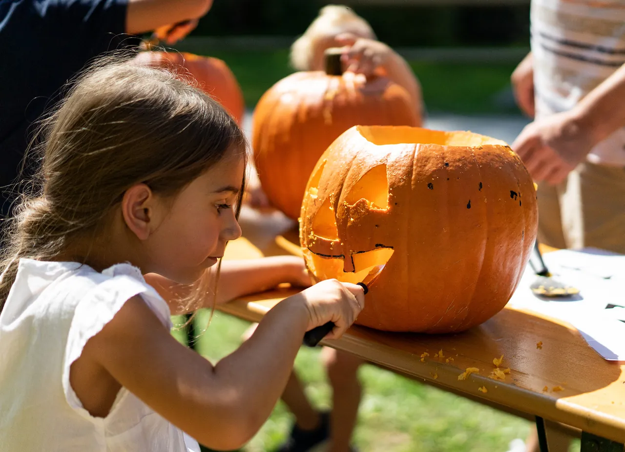 Mädchen schnitzt einen Kürbis beim Halloween-Programm im Ravensburger Spieleland
